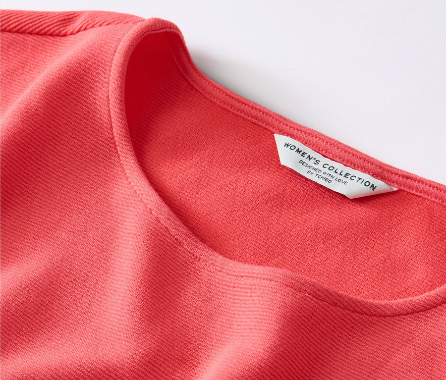 Detailansicht eines korallenroten Blusenshirts.