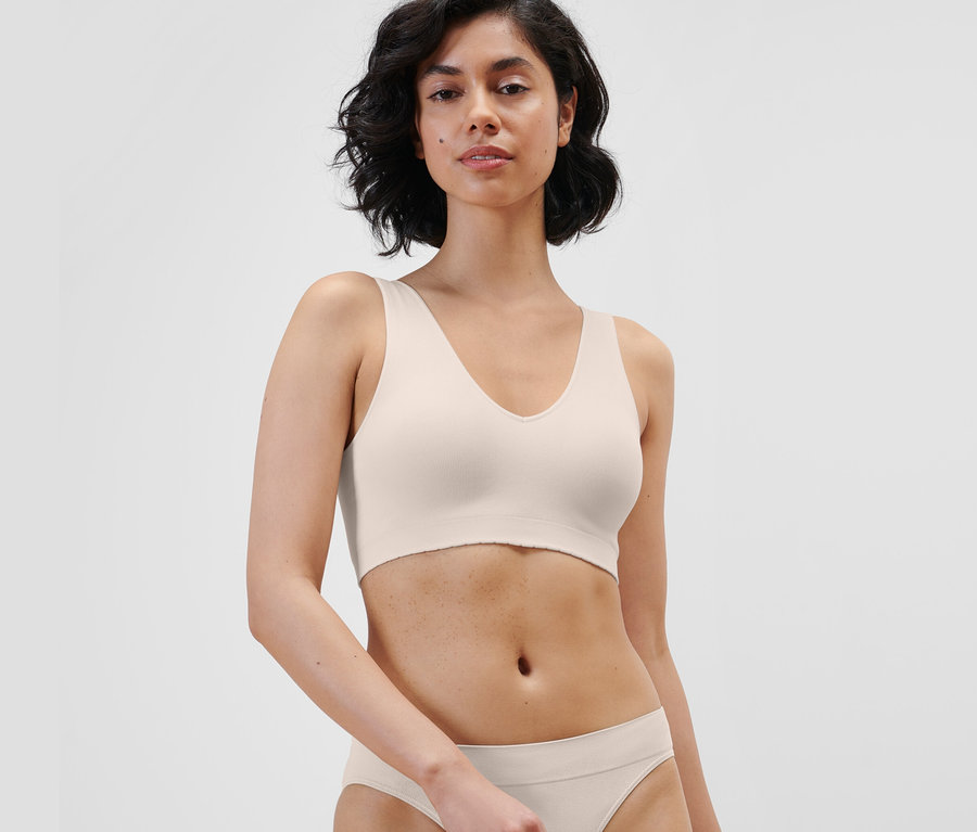 Frau trägt ein creme Seamless-Bustier und Unterteil.