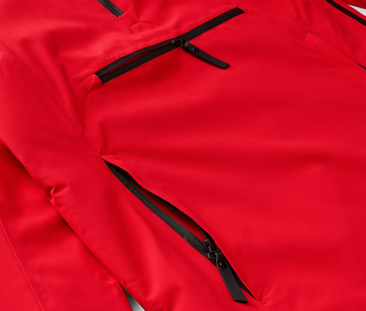 Detail einer roten Jacke mit schwarzen Reißverschlüssen an den Taschen.