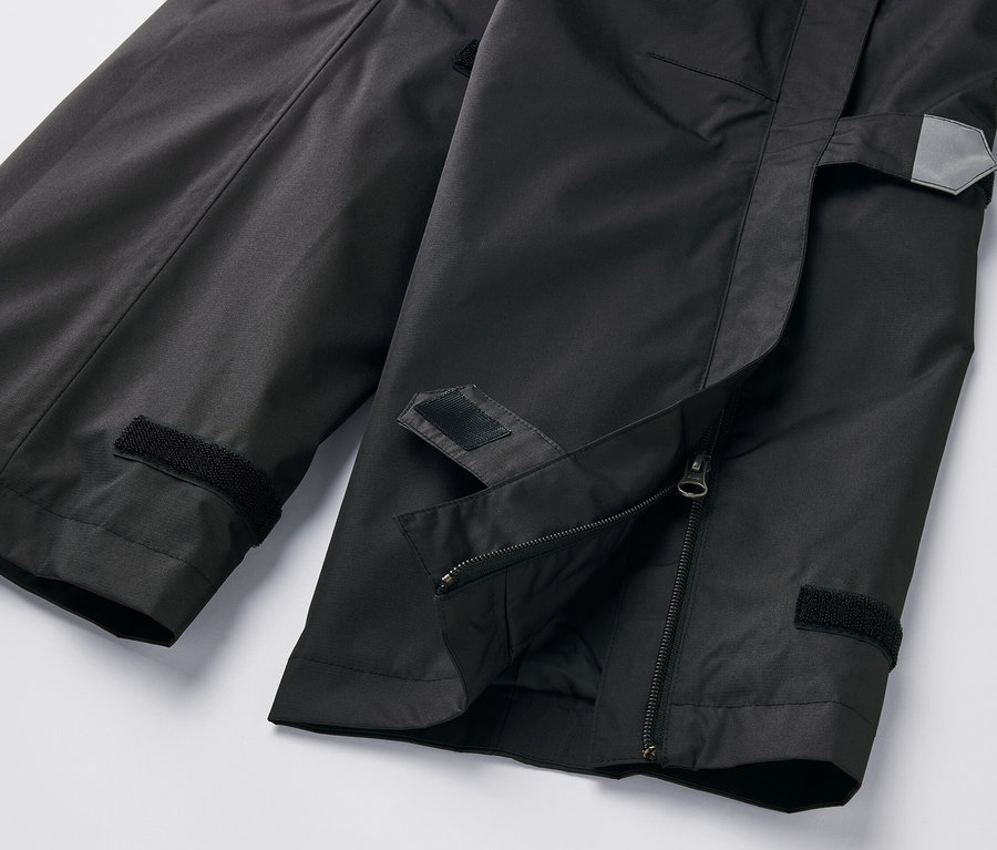 Detailaufnahme einer schwarzen High-Tech-Regenhose mit Reißverschluss und Klettverschluss.