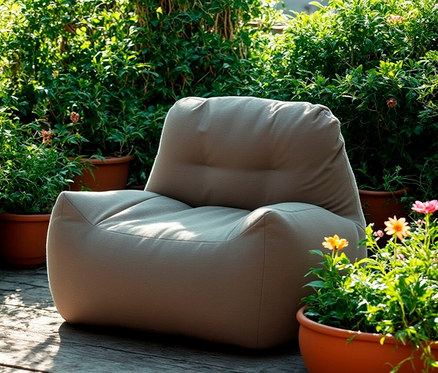 DOMO Collection Loungesessel mit Sunbrella®-Stoff, Flanelle steht im Freien, umgeben von Pflanzen.