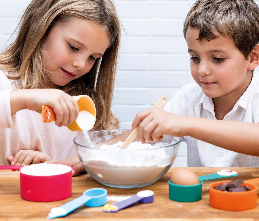 Kinder benutzen Messbecher aus dem Chefclub Dessert und Keks-Back-Set beim Backen.
