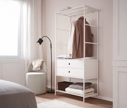 Ein Drehhocker mit Rückenlehne steht neben einer weißen Garderobe »KLAAR« mit 2 Schubladen in einem Schlafzimmer.