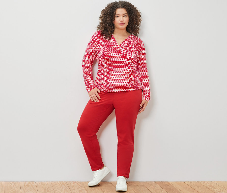 Frau posiert in einem roten, bedruckten Blusenshirt und einer roten Joggpants.