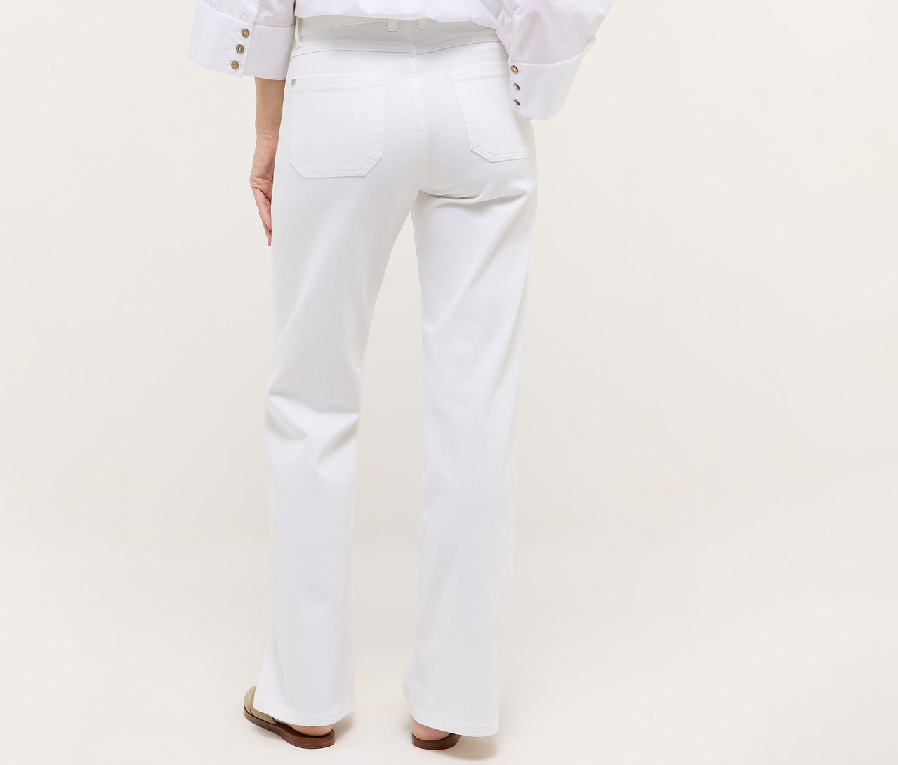 Rückansicht einer Frau, die eine weiße Angels Denim »Liz Urban« Wide Leg Jeans und Sandalen trägt.