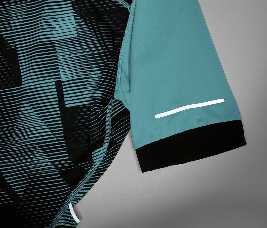 Nahaufnahme eines Radsporttrikots mit türkisfarbenem Ärmel, schwarzem Bündchen und reflektierendem Streifen.