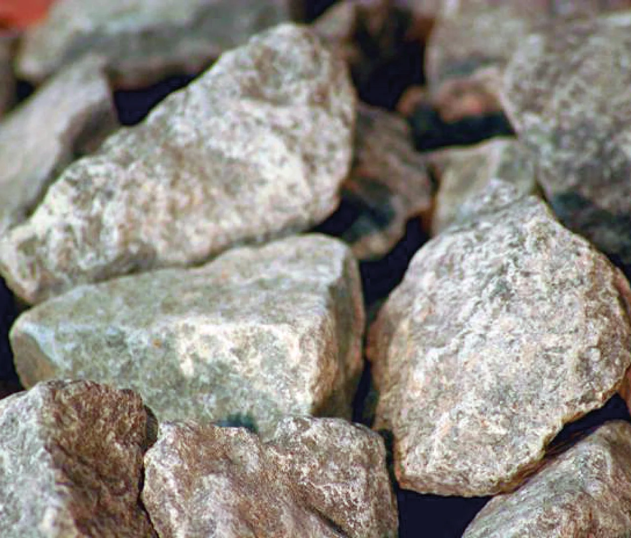 Haufen unregelmäßig geformter, hellgrauer bis brauner Steine mit rauer Oberfläche.