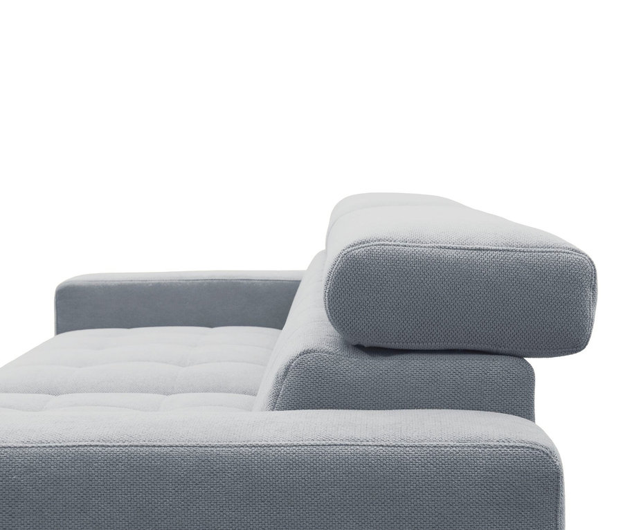Nahaufnahme eines hellgrauen Sofas mit strukturierter Oberfläche, sichtbarer Armlehne, getufteter Sitzfläche und verstellbarer Kopfstütze.