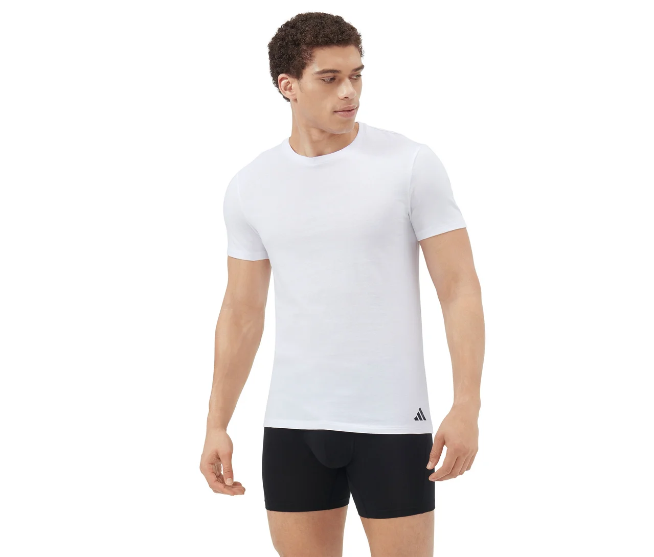 Mann steht, trägt ein weißes Kurzarm-T-Shirt und schwarze Boxershorts, blickt nach rechts vor weißem Hintergrund.