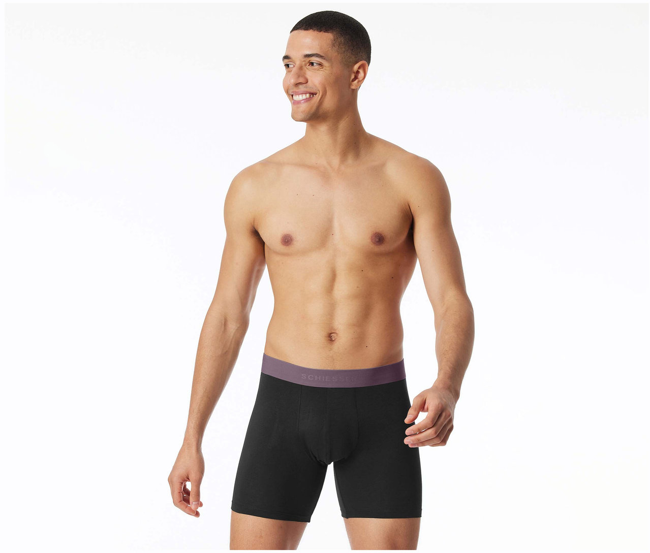Mann trägt schwarze, lange SCHIESSER Slipboxer mit lila Bund und lächelt.
