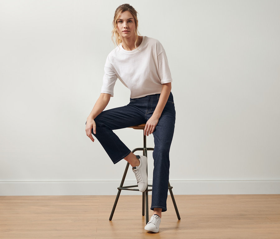 Frau sitzt auf einem Hocker und trägt eine Straight-Denim »Fit Kira«, darkblue denim.