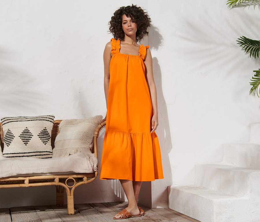 Frau posiert stehend in einem orangefarbenen Popeline-Kleid.