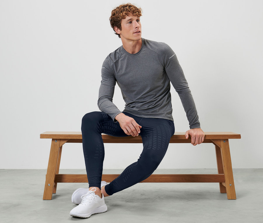 Mann sitzt auf einer Bank und trägt eine Lauftight.