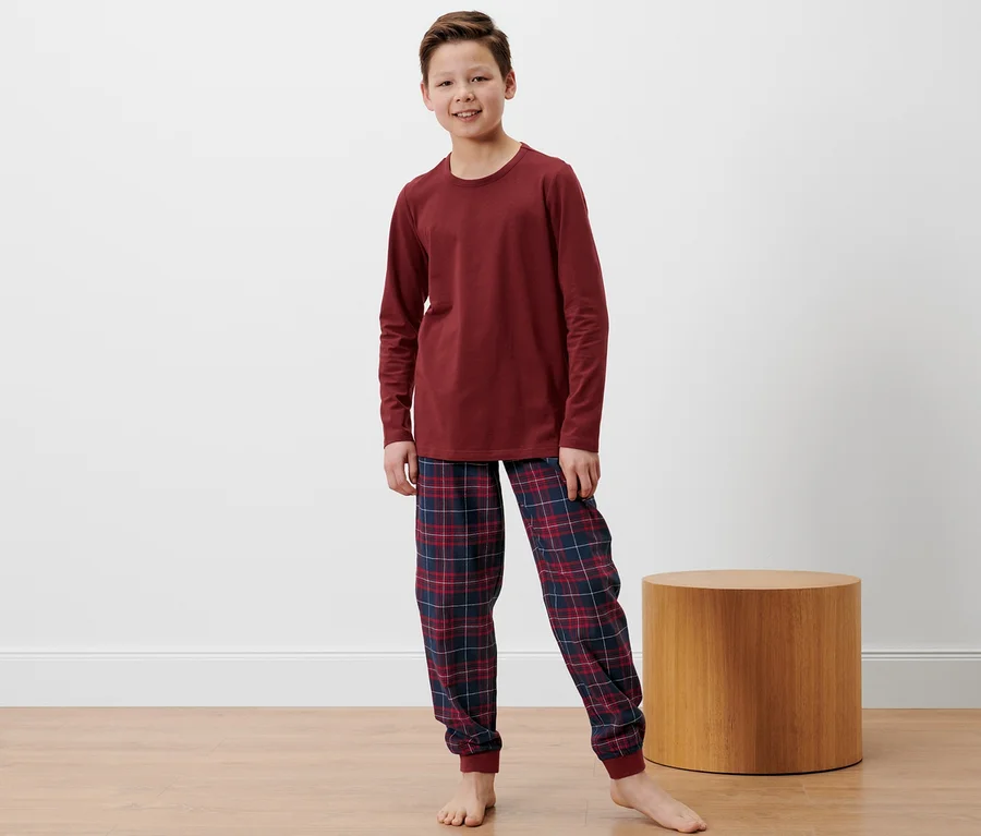 Ein Junge steht und trägt einen Kinder-Flanell-Pyjama.