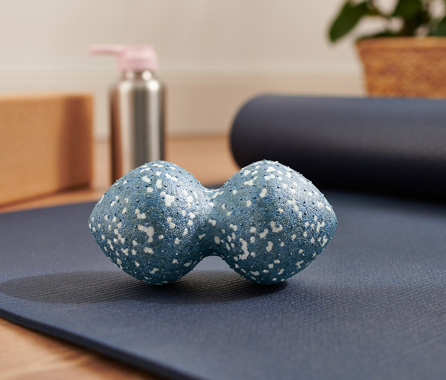 Ein blauer Duo-Massageball liegt auf einer blauen Yogamatte.