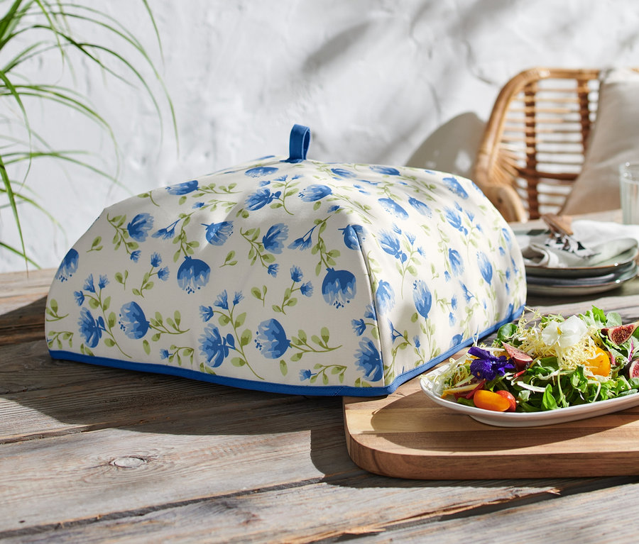 Thermo-Abdeckhaube mit blauen Blumen auf einem Holztisch.