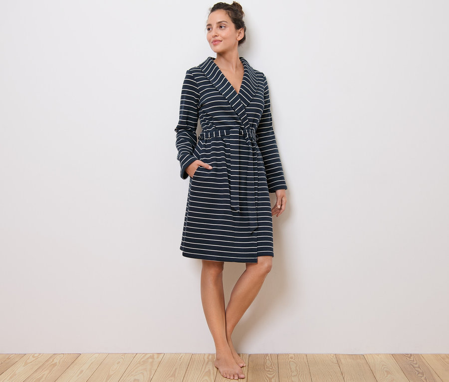 Frau steht und trägt einen Morgenmantel mit Streifen.