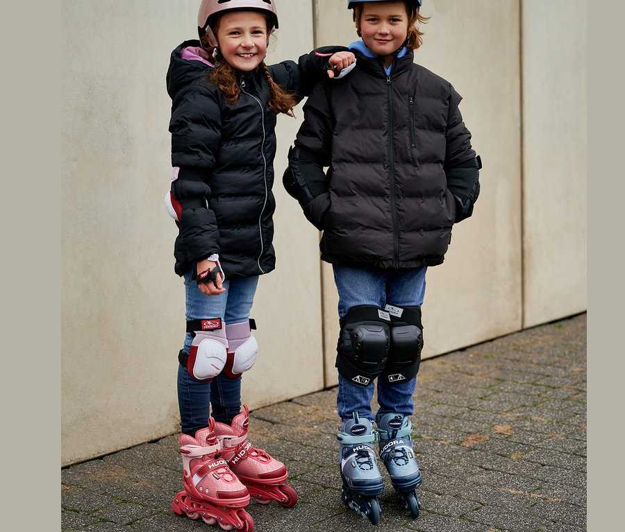 Zwei Kinder in Jacken und Schutzausrüstung stehen nebeneinander auf HUDORA Inline Skates »Leon 2.0«.