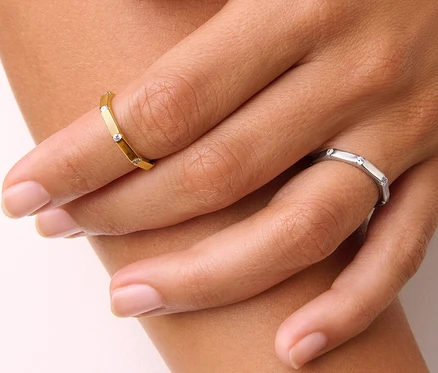 Detailaufnahme einer Damenhand, die einen goldenen 925 Silber Ring Octagon und einen 925 Silber Ring Octagon trägt.