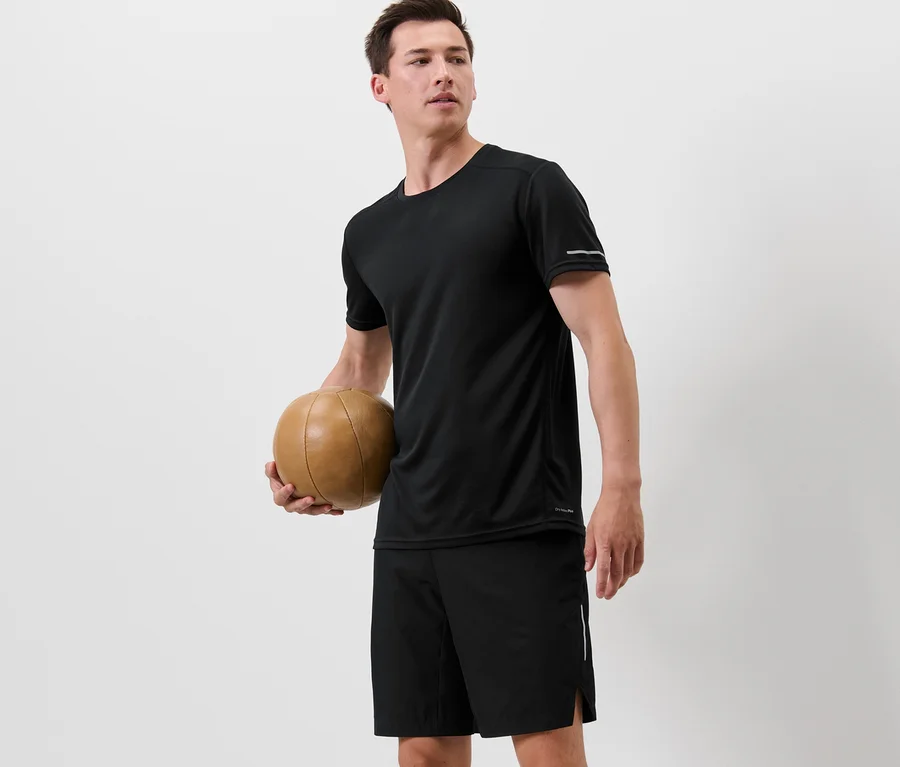 Mann hält einen Basketball und trägt ein schwarzes Funktionsshirt.