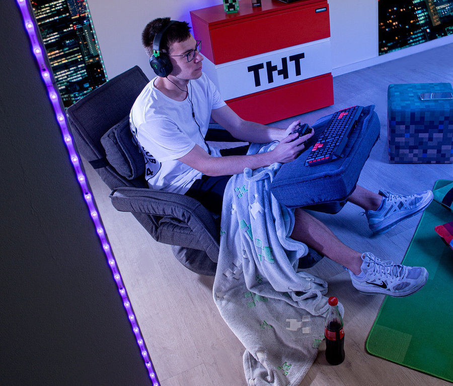 Ein junger Mann sitzt in einem roba Minecraft Loungesessel mit Beinen und Armlehne und spielt ein Videospiel.