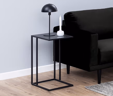 Schwarzes Sofa mit beigen Kissen in einem Wohnzimmer mit einem schwarzen Beistelltisch in C-Form.