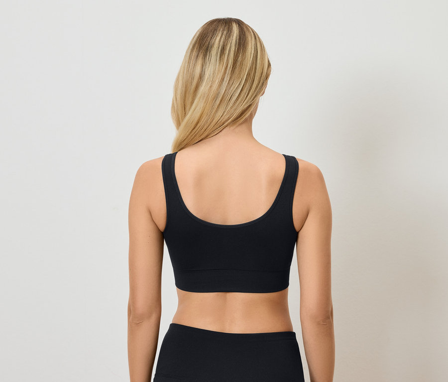 Rückansicht einer blonden Frau mit schwarzem Sport-BH und Hose.