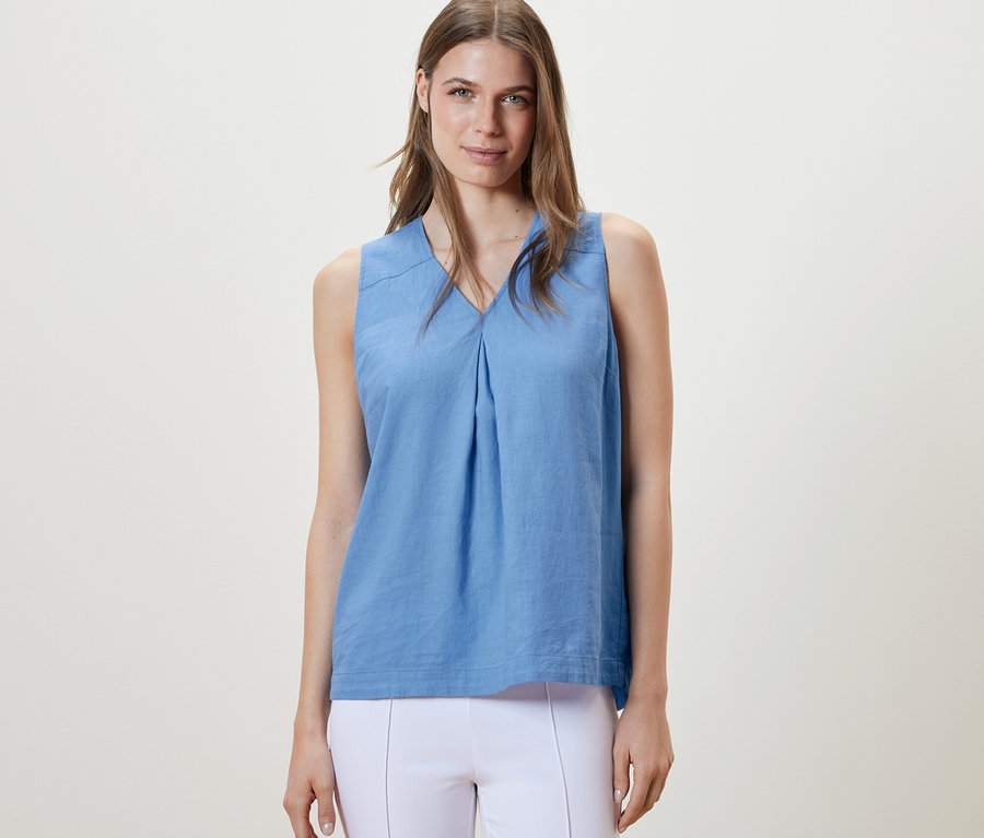 Frau trägt eine hellblaue, ärmellose Leinenbluse.