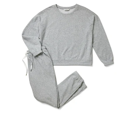 Graues Sweatshirt und Jogginghose liegen auf weißem Hintergrund.