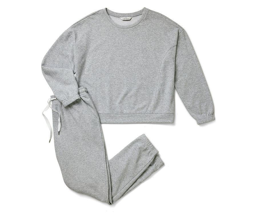 Graues Sweatshirt und Jogginghose liegen auf weißem Hintergrund.