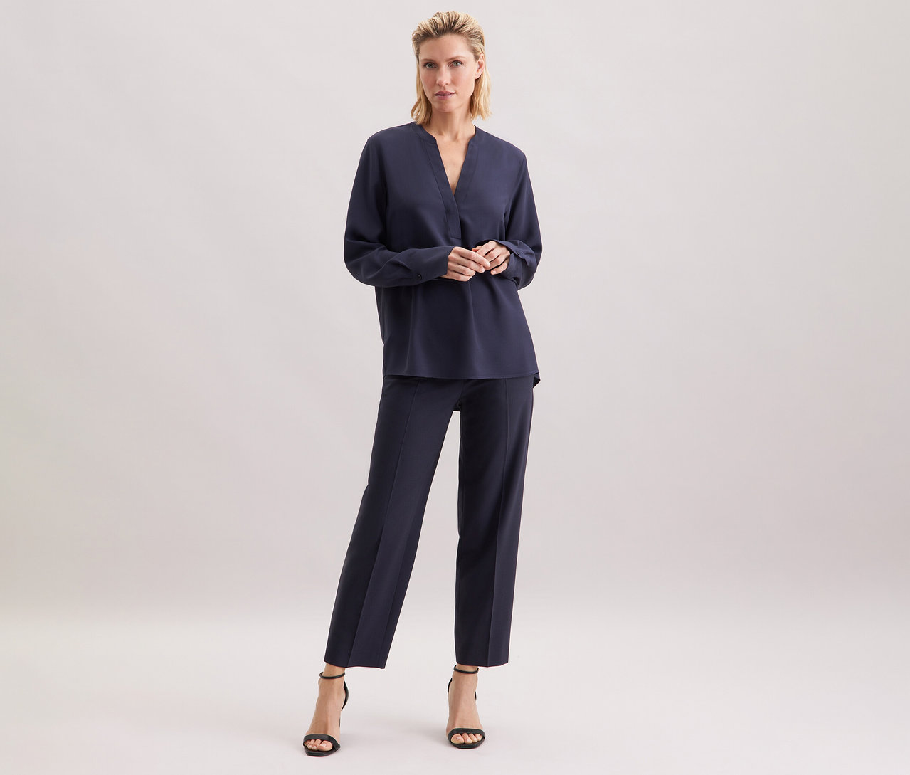 Frau steht und trägt eine marineblaue Seidensticker Tunika aus Viskose.