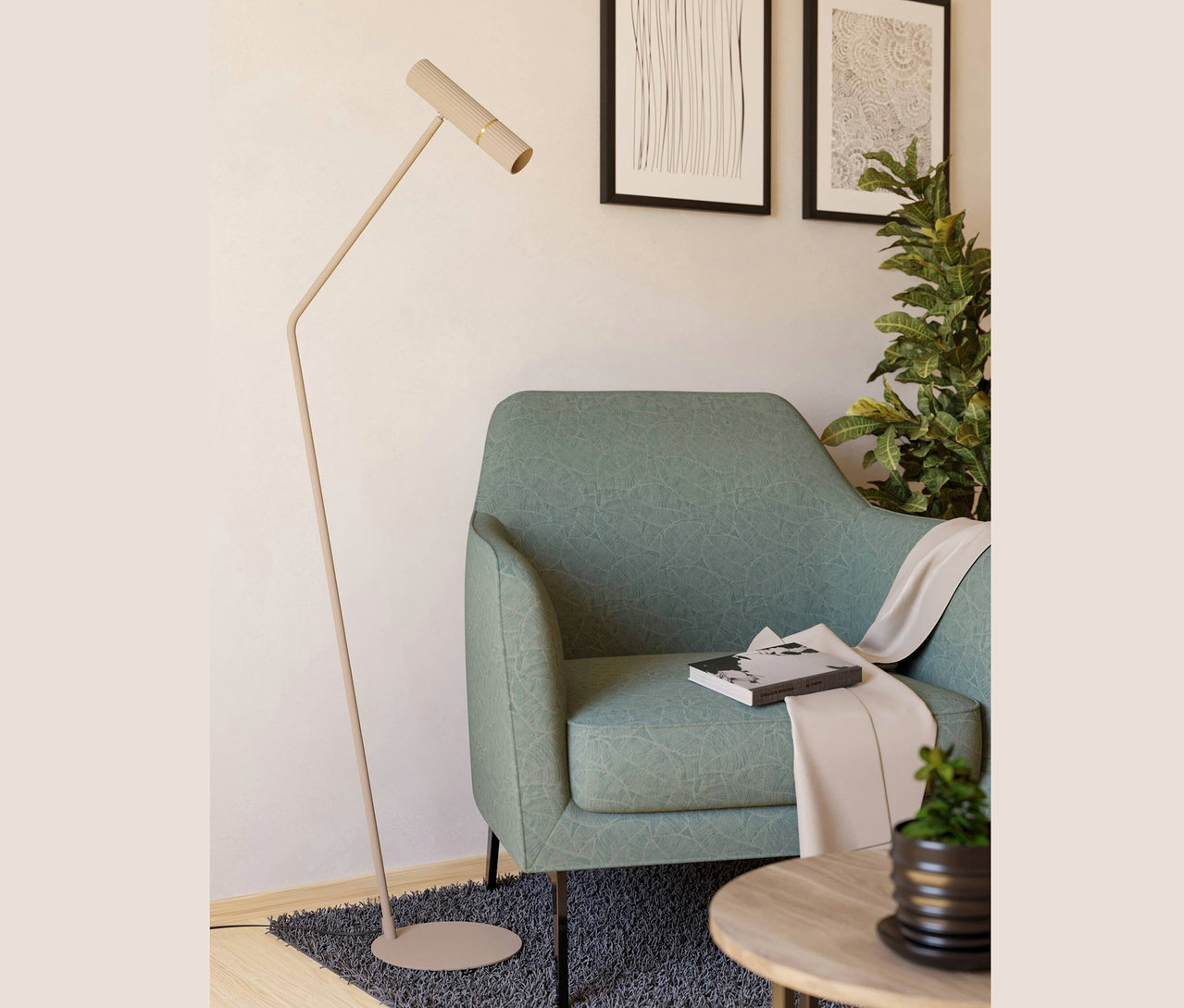 Ein grüner Sessel mit einem Buch und einer beige Decke, daneben eine Stehlampe und ein Tisch mit einer Pflanze. An der Wand hängen zwei Bilder.