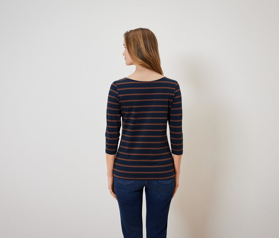 Rückansicht einer Frau in einem blau-braun gestreiften Oberteil und blauen Jeans.