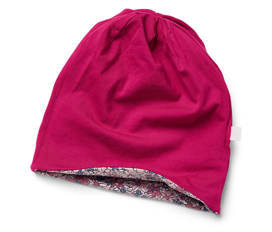 Eine pinke Mütze mit Blumenfutter liegt auf einem weißen Hintergrund.