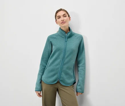 Frau trägt eine türkisfarbene Fleecejacke und olivgrüne Hosen.