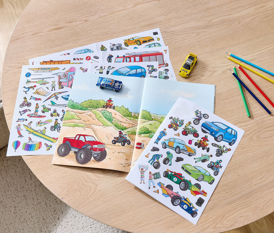 Auf einem Tisch liegen ein geöffnetes Stickerbuch »Fahrzeuge« und Buntstifte.