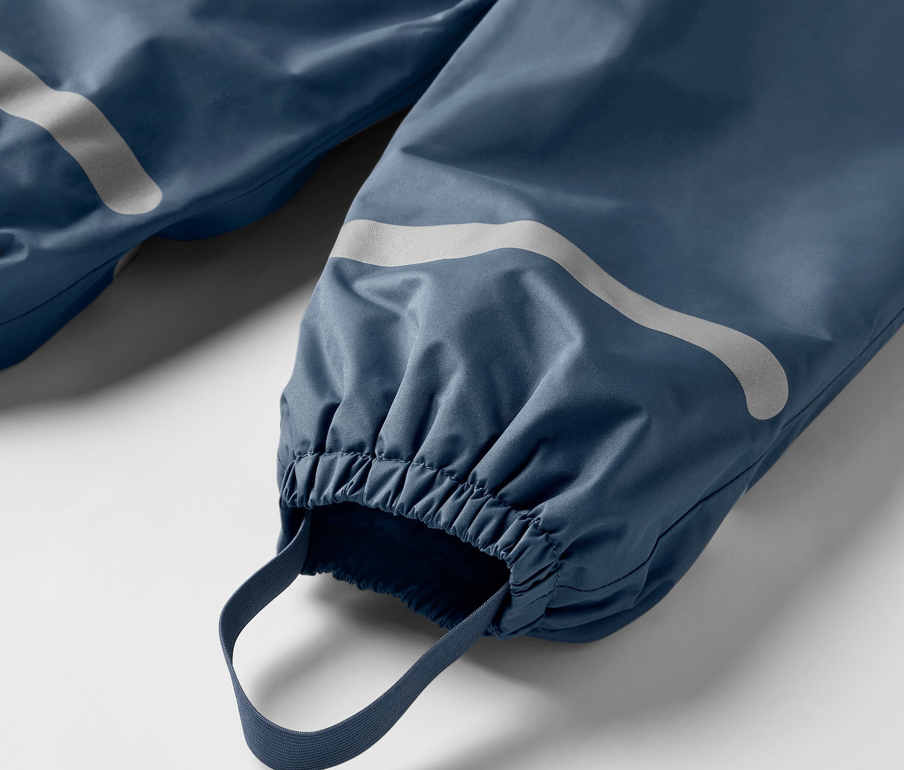 Detailaufnahme einer blauen Kinder-Thermo-Regenhose mit Reflektoren und elastischen Bündchen.