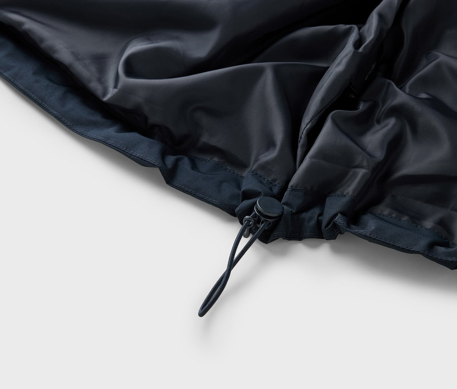 Detailansicht der Innenseite einer dunkelblauen Jacke mit Kordelzug.