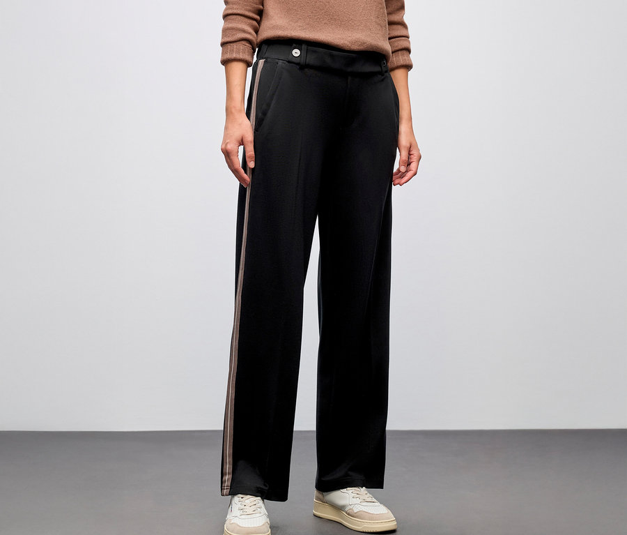 Person trägt eine schwarze Street One Straight Leg Hose mit Gallon und braunen Pullover.