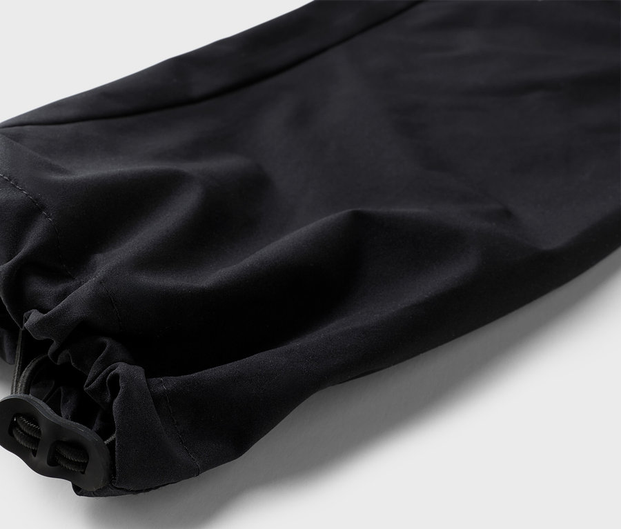 Detailaufnahme eines schwarzen Hosenbeins mit elastischem Saum und Kordelzug.