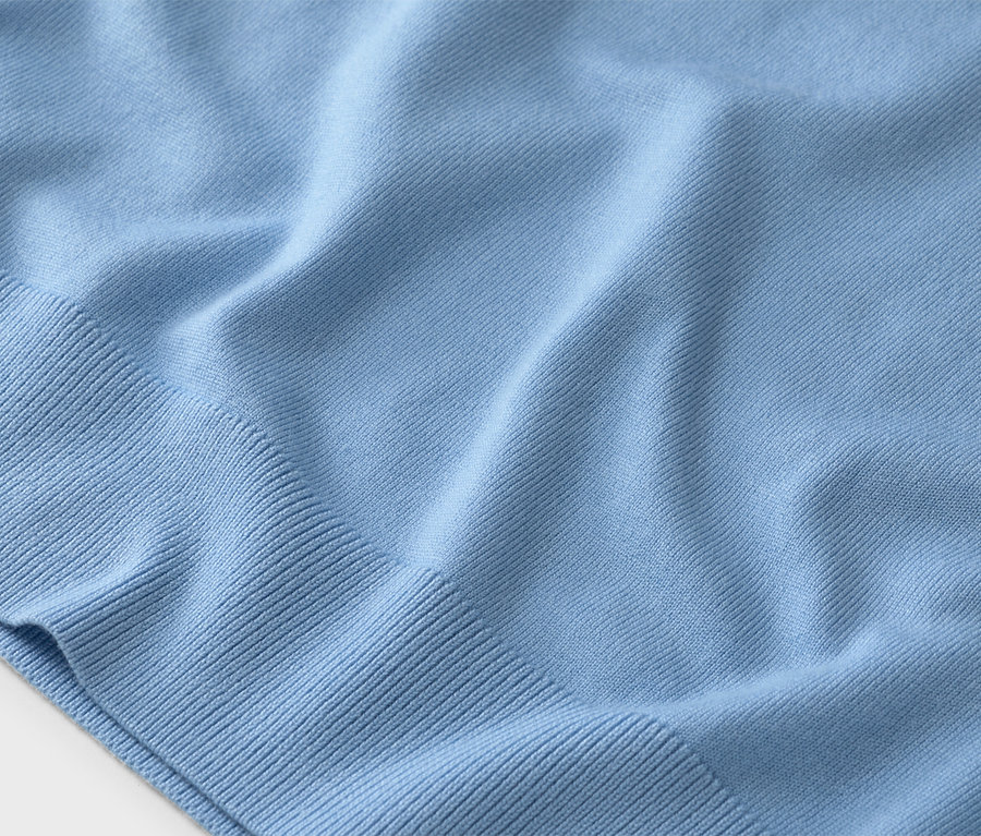Nahaufnahme eines hellblauen Strickpullovers mit Rippstrickbündchen.