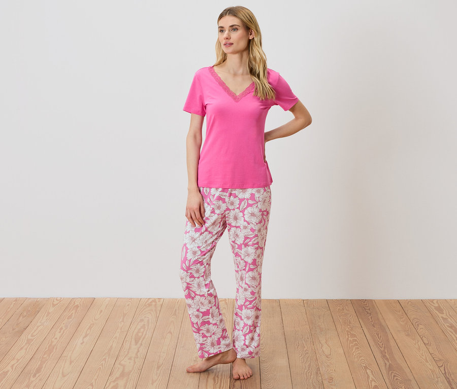 Frau in einem pinken T-Shirt mit Spitzendetails und einer geblümten Pyjamahose.