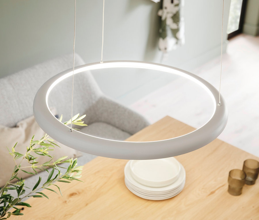 Leuchtende SCHÖNER WOHNEN-Kollektion Pendelleuchte "Quillo" in Sandbrise über einem Holztisch mit Tellern, Gläsern und einer Pflanze.