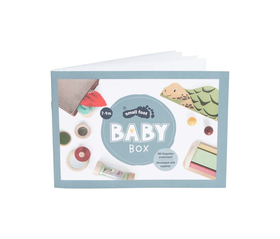Offene small foot Baby-Box, 7–9 Monate, mit bunten Holzspielzeugen, einem Rassel, Stoffelementen und einer Schildkrötenillustration.