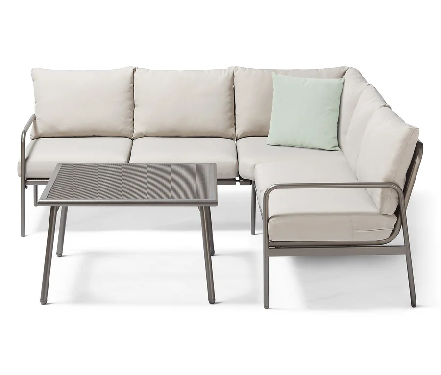 Ein Garten-Dining-Lounge-Set, Ecke, mit beigen Polstern und einem Tisch mit Metallrahmen.