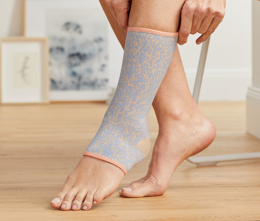 Frau zieht eine Fußgelenkbandage an.