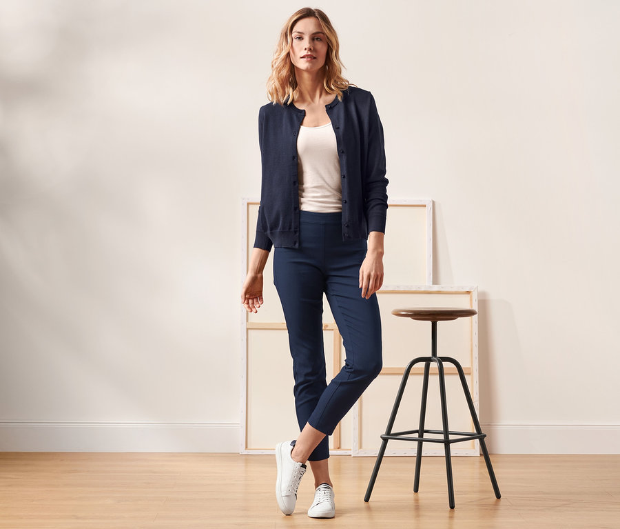 Frau posiert in marineblauer Strickjacke und dunkelblauer Stretchhose.