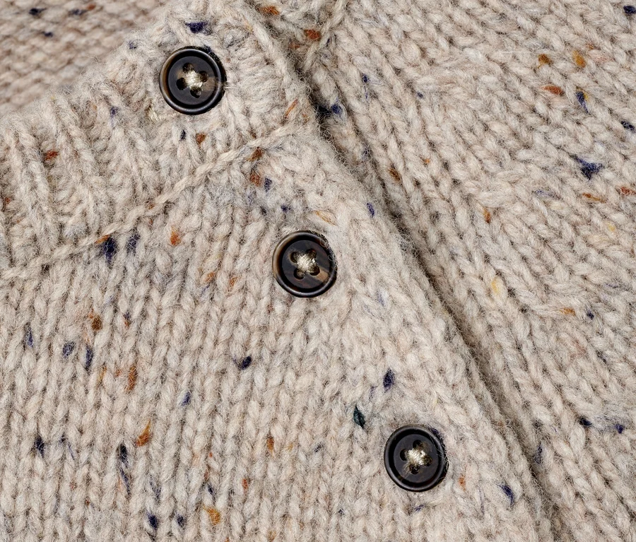 Detailansicht eines Strickpullovers mit RWS-Wolle und braunen Knöpfen.