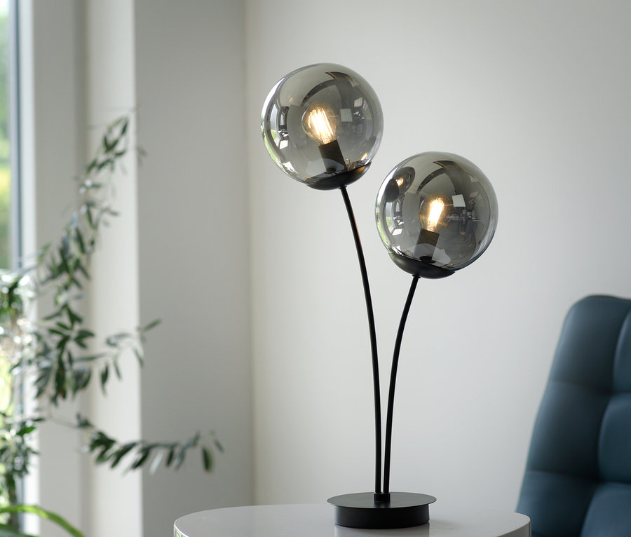 Schwarze JUST LIGHT Tischleuchte »Big Widow« mit zwei Glaskugeln steht auf einem weißen Tisch.