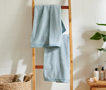 Zwei hochwertige hellblaue und blaue Handtücher hängen auf einer Holzleiter im Badezimmer.